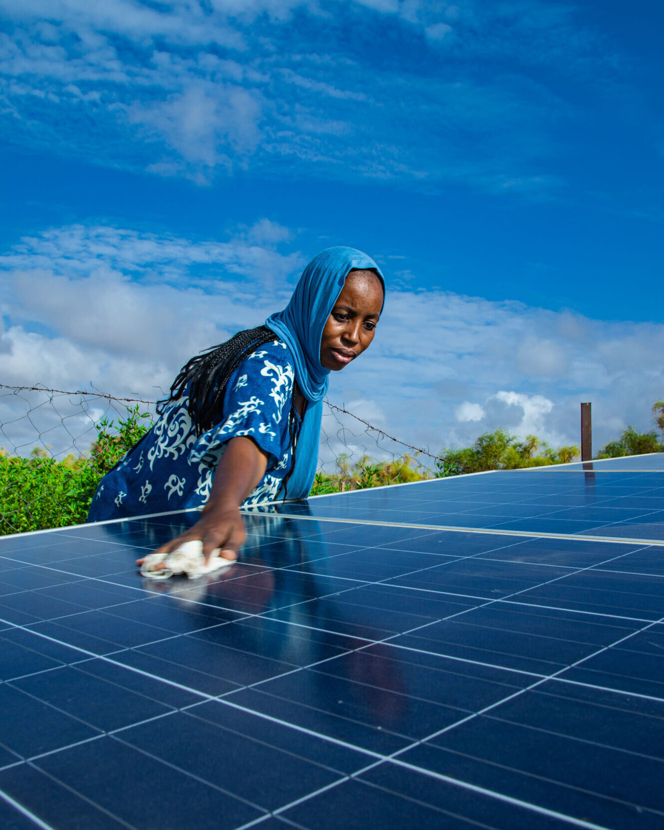 Solar wells to address the problem of drought, a woman cleaning a solar energy panel